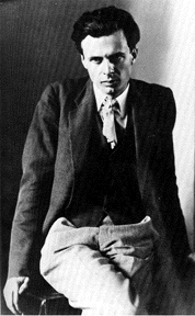 Monochrome portrait of Aldous Huxley sitting on a table, facing slightly downwards.