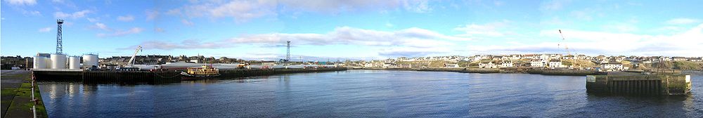 Wick Harbour, Scotland, with the ex-RMAS Fleet Tender Ilchester and windmill blades to the left and the river in the center.Zoom: with Flash player / without